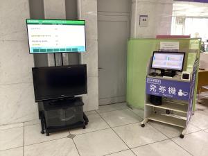番号発券機と番号案内表示モニターが並んでいる様子